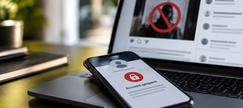 Smartphone mit gesperrtem Social-Media-Account vor einem Laptop- Gesetz gegen digitale Gewalt, Accoundsperren und Schutz vor Deepfakes